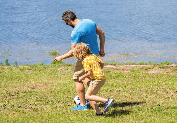 dad and son enjoying childhood adventures outdoor. dad and son playing football during their childhood. Childhood memories of son and his dad. dad have fun with his son. Outdoor escapades.