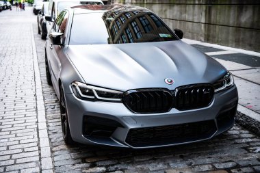 New York, ABD - 15 Temmuz 2023: BMW F90 M5 gri renkli araba park edilmiş, köşe manzaralı.