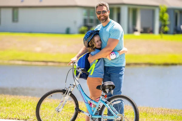 fathers parenting with son outdoor. childhood of son supported by fathers care. father hug son on bicycle at fathers day. active father setting a example for fathers son. family relationship.