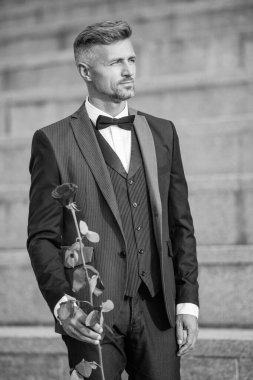 Özel durum konsepti. Özel durumlar için gül taşıyan boz adam. Smokinli adam özel bir gün için dışarı çıktı..