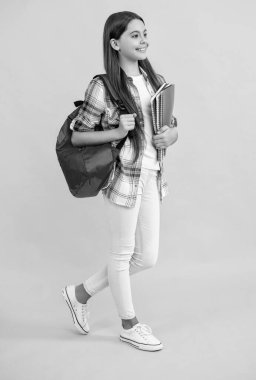 photo of happy teen school girl with backpack. teen school girl isolated on yellow. teen school girl in studio. teen school girl on background.