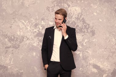 Pozitif iş adamının telefon giysisi üzerindeki konuşmasının fotoğrafı. Grey 'de izole edilmiş başarılı bir iş adamı konuşması. Stüdyoda iş adamı telefonda konuşur. İş adamı arka planda konuşur.