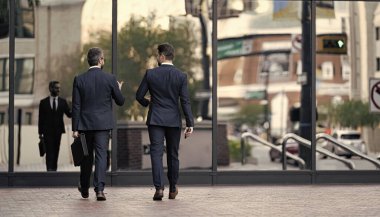 İş adamlarının sokaktaki arka planı, pankart. İş arkadaşlarının takım elbise giydiği bir fotoğraf. İş arkadaşları yürüyor. İş adamları dışarıda çalışıyor..