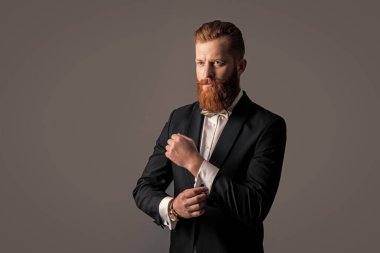 Smokinli beyaz bir adamın stüdyosu çekiliyor. Smokin giyen bir adam. Smokin resmi kıyafet. Smokinli sakallı adam gri arka planda izole edilmiş..