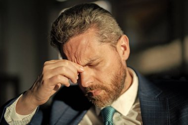 Yorgun iş adamının migren ağrısı var. Hüsrana uğramış iş adamının fotoğrafı migren yapar. Hüsrana uğramış iş adamının evde migreni var. Hüsrana uğramış iş adamının gün boyunca migreni tutar..