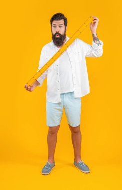 Şok olmuş bir adam okulun hükümdarı sarıda izole edilmiş. Stüdyoda okul yöneticisi var. Arka planda okulun yöneticisi var. Man Hold okul hükümdarının fotoğrafı..