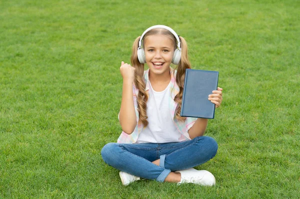 happy teen girl in music headphones. education through self reading book. audio book or ebook. teen girl lifestyle. relax in park. music education while listening. lifestyle of girl outdoor.
