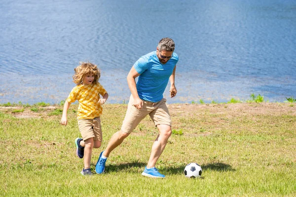 dad have fun with his son. challenges of fatherhood. dad and son enjoying childhood adventures outdoor. dad and son playing football during their childhood. Childhood memories of son and his dad.