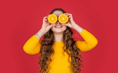 Komik çocuk mor arka planda portakal meyvesi tutuyor..