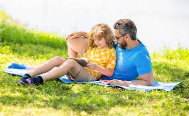 çocukluk okulu eğitimi. Oğlu ve babası yazın kaynaşıyorlar. Baba ve oğul eğitimi almış. Baba oğul eğitimini tabletle şekillendirir. Baba ve oğul parkta dinleniyor. Mutlu ebeveyn okumaları.
