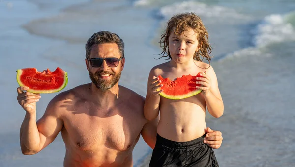 Father dad and son eating watermelon. happy dad and son on fatherhood vacation. single dad father with son at the beach. Loving dad and son enjoying fatherhood time together at sea.