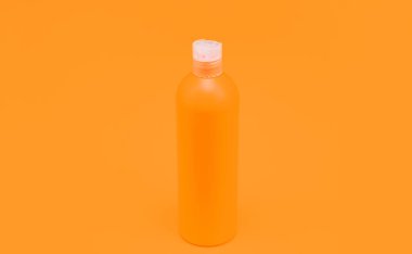 sarı arka planda turuncu şampuan şişesi, hijyen.