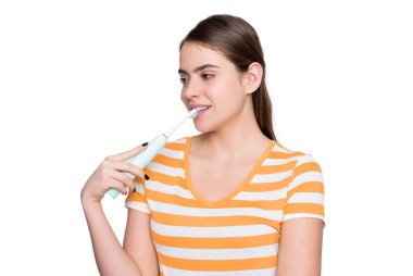 Beyaz arka planda elektrikli diş fırçası olan gülümseyen genç kız..