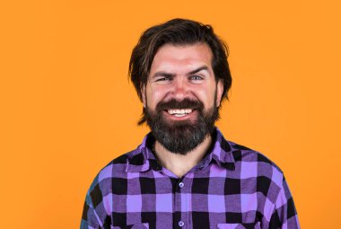 Güzel beyaz bir gülümseme. Sıradan bir adam insani duygularını ifade eder. Uzun saçlı ve bıyıklı mutlu bir hippi. Erkek güzellik ve moda. Berber dükkanı konsepti. Kareli gömlekli sakallı adam..