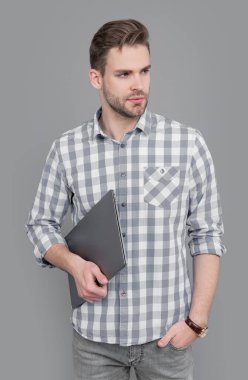 Dizüstü bilgisayarı tutan ciddi bir adam. Dizüstü bilgisayarı olan serbest çalışan biri. Dizüstü bilgisayar kullanıcı stüdyosu gri renkte izole edildi.