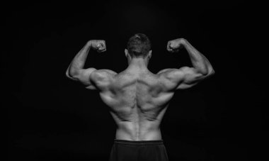 Siyah stüdyoda vücut geliştiren kaslı adam. Vücut geliştiren kaslı adam arka planda. Vücut geliştiren kaslı adamın fotoğrafı. Vücut geliştirici, kaslı, siyah sırtlı..