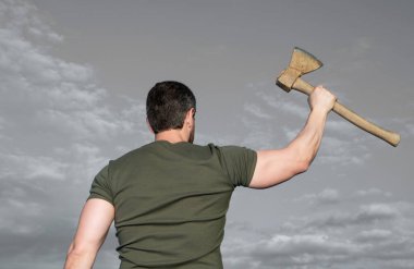 Baltalı bir adamın arka görüntüsü. Adam baltayı tutuyor. Gökyüzündeki vahşi adam.