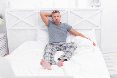 Sabahları yatağında dinlenen, rahat pijamalı, ciddi bir adam..