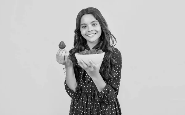 stock image positive teen girl hold strawberry bowl on yellow background.