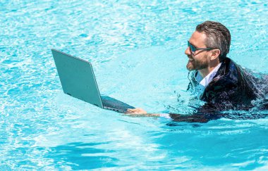 Yüzme havuzunda dizüstü bilgisayarı olan iş adamı. Yaz tatilindeki iş adamı. Yüzme havuzunda dalgıç kıyafetli bir iş adamı. Uzaktan kumanda çalışıyor. Yaz iş hayalleri. Başarılı adam. iş hafta sonu.