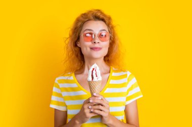 Stüdyoda dondurmalı gülümseyen kız. Arka planda dondurma külahı olan kız. Yazın külahta dondurmalı bir kızın fotoğrafı. Dondurmalı kız sarıda izole edilmiş..