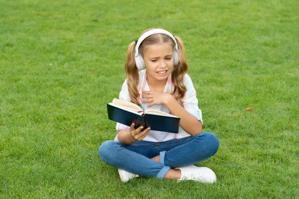 teen girl lifestyle. tween dislike the book. relax in park. music education while listening. lifestyle of teenager girl outdoor. teen girl in music headphones. education through self reading book.