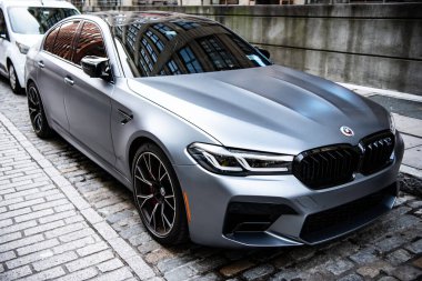 New York City, ABD - 15 Temmuz 2023: BMW F90 M5 gümüş renkli araba park edilmiş, köşe manzaralı.