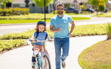 Babalar gününde bisikletli baba oğul. Aktif baba, babasının oğluna örnek oluyor. Baba oğul açık havada ebeveynlik yapıyor. Babasının bakımıyla desteklenen bir çocukluk. etkin hafta sonları.