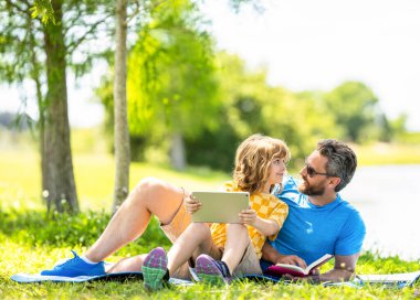 çocukluk okulu eğitimi. Oğlu ve babası yazın kaynaşıyorlar. Baba ve oğulun ailesi. Baba oğul eğitimini kitap tabletiyle şekillendirir. Baba ve oğul parkta rahatlayın. Doğa sınıf gibidir..