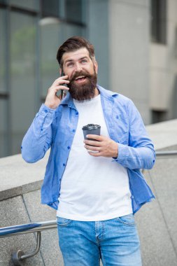 Neşeli adam dışarıda akıllı telefonda konuşuyor. Adam sokakta akıllı telefondan konuşuyor. Akıllı telefondan konuşan adamın fotoğrafı. Adam dışarıda akıllı telefondan konuşuyor..