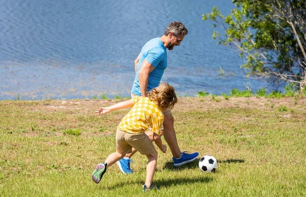 Baba ve oğul arkadaşça bir futbol maçının tadını çıkarıyorlar. Oğlunun babasıyla oynadığı mutlu bir çocukluk. baba ve oğul yaz aktivitesi. Oğlu dışarıda babasıyla vakit geçiriyor. Açık havayı kucaklamak..