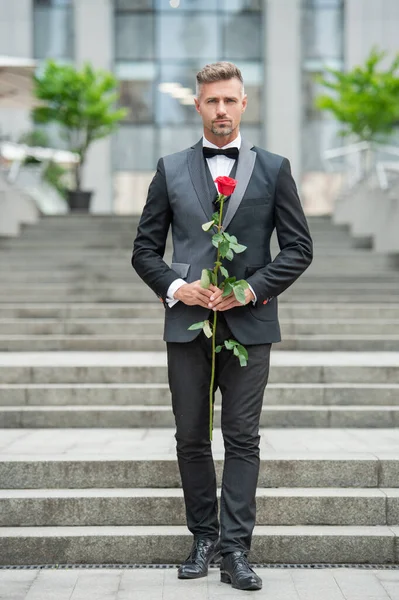 special occasion formalwear. caucasian man with rose for special occasion. tuxedo man outdoor at special occasion.