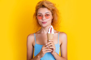 Yazın külahta dondurmalı bir kadın resmi. Külahta dondurması olan kadın sarıda izole edilmiş. Stüdyoda dondurmalı bir kadın var. Arka planda dondurma külahlı kadın.