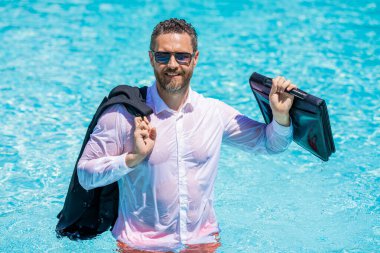 Yaz tatilindeki iş adamı. Dışarıda başarılı bir iş adamı. Takım elbiseli, bilardo çantalı bir iş adamı. İşadamı başarılı bir anlaşma yaptı. Başarılı bir proje. Yüzme havuzunda iş adamı.