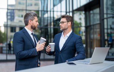 Kahve molasında serbest çalışan iki tüccar. Tüccarlar online olarak dışarıda serbest çalışıyorlar. Ticari tüccarlar dizüstü bilgisayarla serbest çalışıyorlar. Çevrimiçi serbest çalışan tüccarların fotoğrafı.