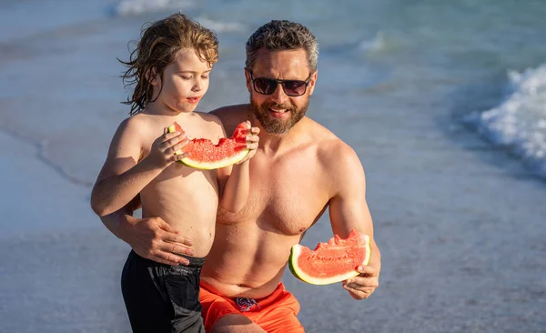 Fathers day. Father dad and son eating watermelon. dad and son on parenthood vacation. single dad father with son at the beach. Loving dad and son enjoying parenthood at sea.