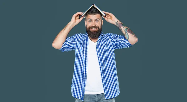 灰色の背景に頭の上に本を持っている幸せなひげ付き男 — ストック写真