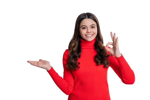 stock image teen girl presenting product with hand. teen girl presenting product on copy space. teen girl show advertisement. here is your advertisement. teen girl directing to advertisement. ok gesture.