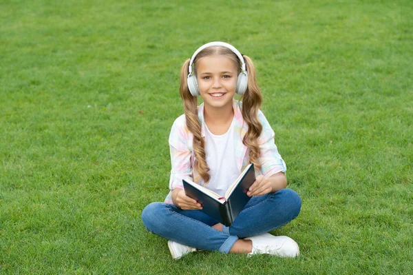 education through self reading book. audio book or ebook. teen girl lifestyle. relax in park. music education while listening. lifestyle of teenager girl outdoor. teen girl in music headphones.