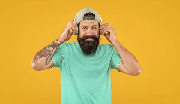 photo of positive man with music headphones. man with music headphones isolated on yellow. man with music headphones in studio. man with music headphones on background.