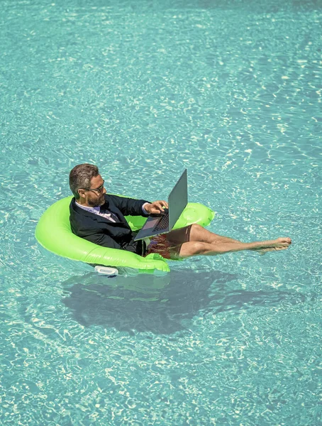 stock image business man trading online with laptop. photo of business man trading online in suit. business man trading online. business man trading online in swimming pool.