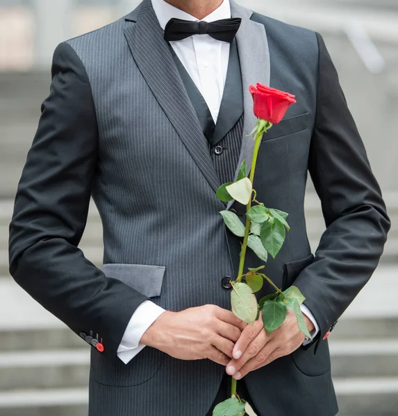 special occasion formalwear. cropped view of man with rose for special occasion. tuxedo man outdoor at special occasion.