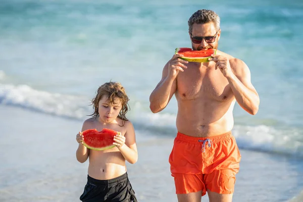 Father dad and son eating watermelon. dad and son on summer vacation. single dad father with child son in childhood. Loving dad and son enjoying quality time together at sea.