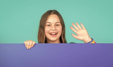 Boş mavi kağıdın arkasında reklam için fotokopi alanı olan mutlu bir çocuk. Merhaba jest.