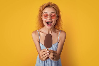 Yazın dondurmalı bir kadının seçici odak fotoğrafı. Dondurmalı kadın sarıda izole edilmiş. Stüdyoda dondurmalı kadın. Arkaplanda dondurma olan kadın..