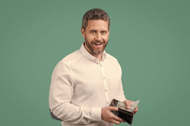 Cüzdanında para kazanan iş adamının fotoğrafı. Mavi arka planda izole edilmiş para kazanan bir iş adamı. İş adamı stüdyoda para kazanıyor. İşadamı para kazanıyor..