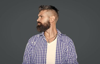 Sakallı adamın profili Gri arka planda kareli gömlek giyer.