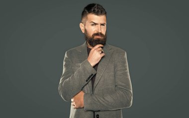 Sakallı düşünceli adam gri arka planda rahat giyinir..