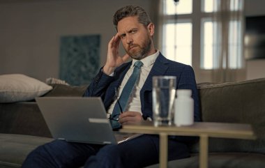 Yorgun iş adamının migren ağrısı var. Yorgun iş adamının fotoğrafı migren yapar. Yorgun iş adamının evde migreni var. Yorgun iş adamının çalışırken migreni tutar..