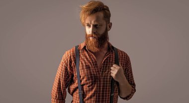 Arka planda pantolon askısı takmış zarif bir hipster. Pantolon askısı takmış hipster bir adamın fotoğrafı. Askılı eski hipster adam gride izole edilmiş. Stüdyoda askılı hipster adam..